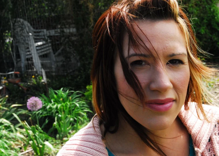 young woman with brown hair and pink  shirt in the garden