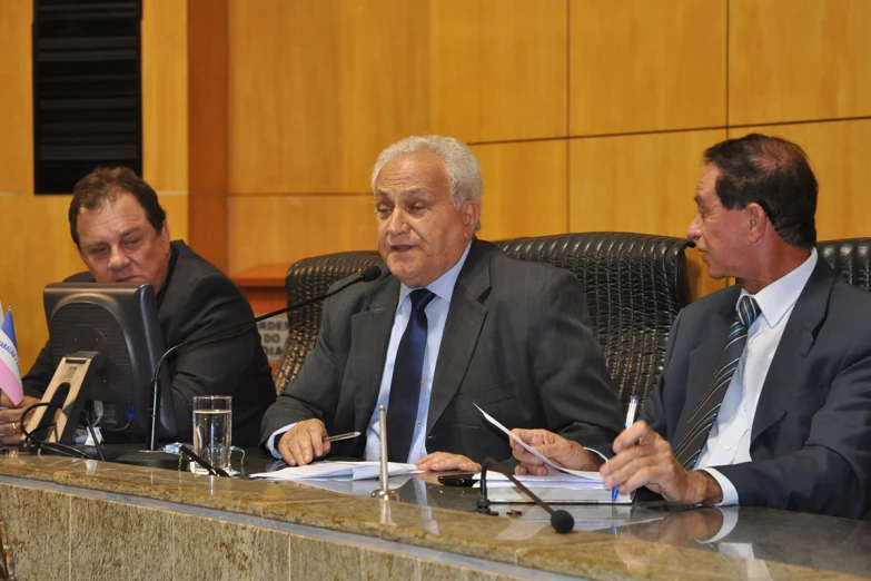 four men in suits and ties are sitting around a table