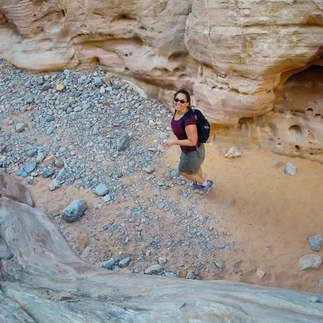 a woman in a hat is standing on rocks