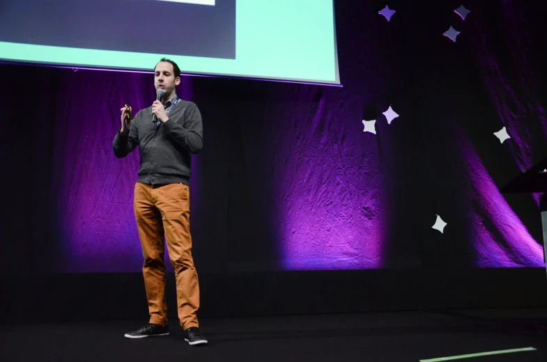 a person standing up in front of a stage speaking