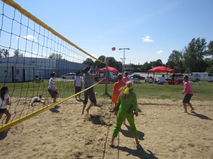 group of people playing volleyball in sandy area