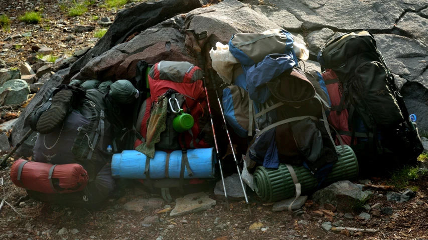 a pile of camping gear sitting near a boulder