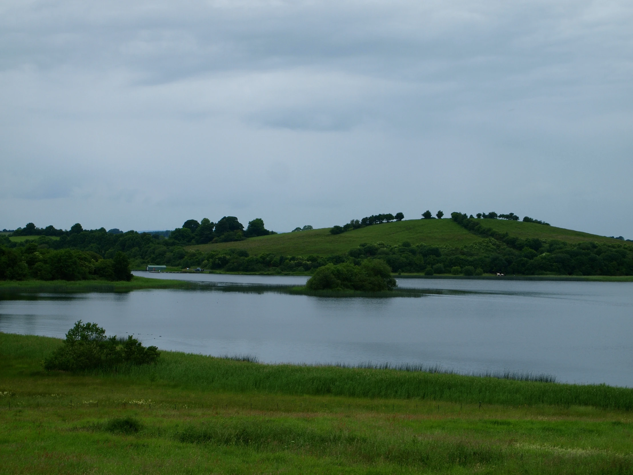 a lake surrounded by green hills in the distance