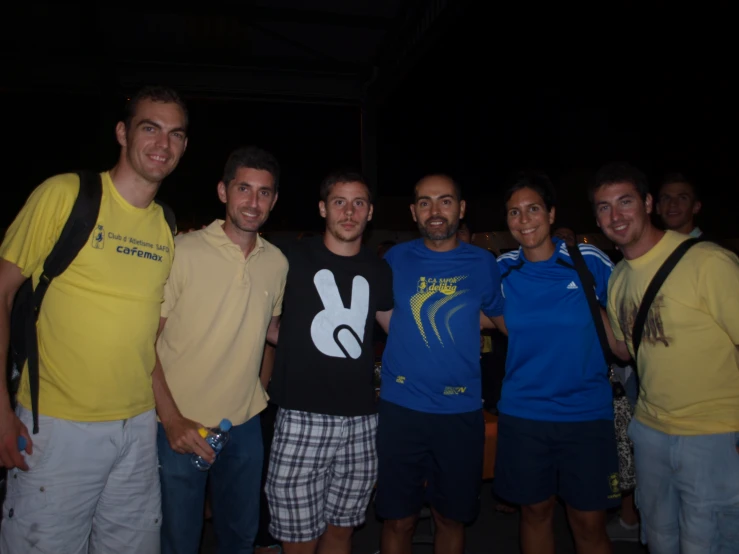 four guys posing together for a picture with another guy in a blue shirt and yellow