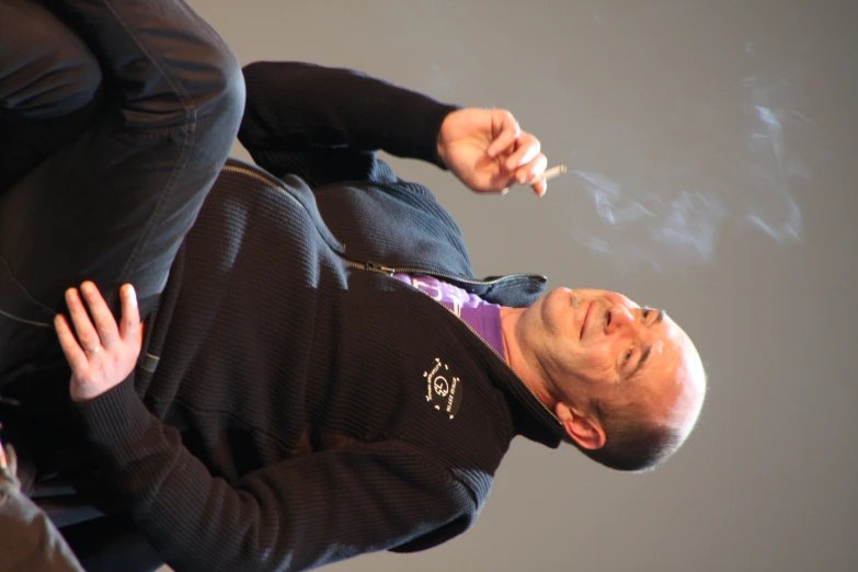 a man sitting down and smoking a cigarette