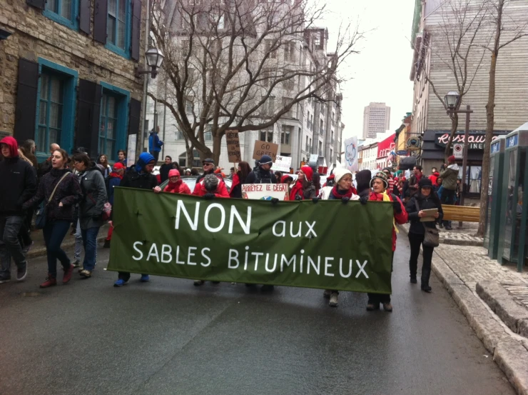 several people are walking down the road holding a banner