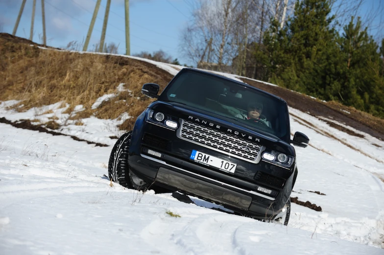 a black vehicle driving through some snow