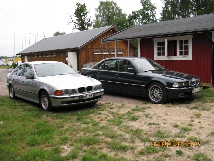 the two black bmw cars are parked near a house