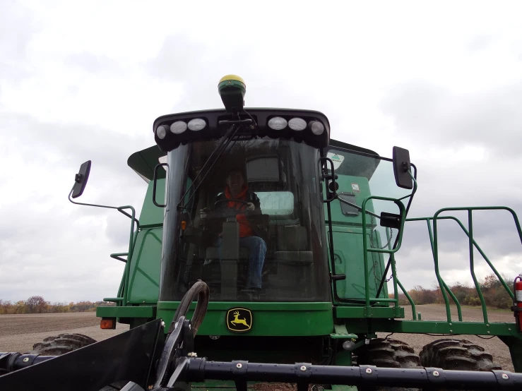 a man standing on top of a large green tractor