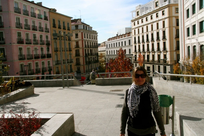 a lady walking on a street next to some very tall buildings