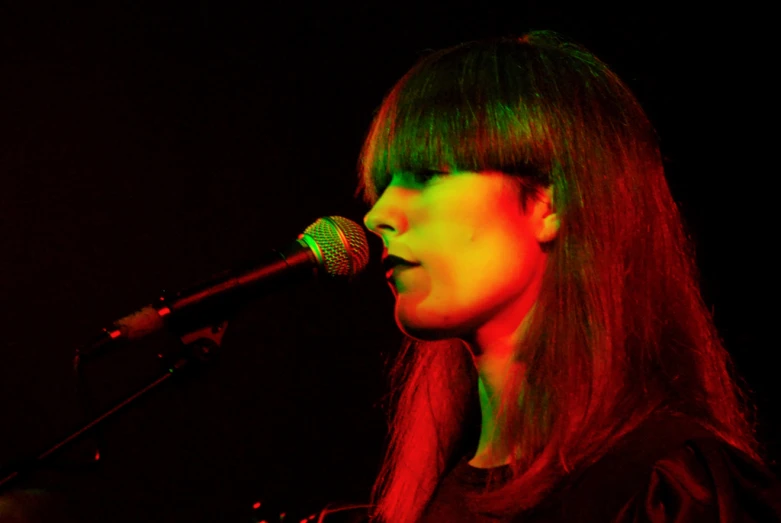 a young woman singing into a microphone with long straight hair