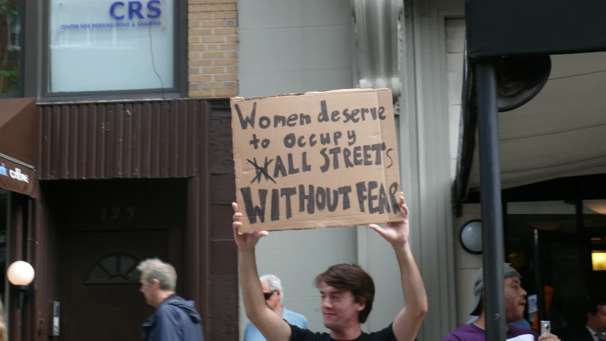 a woman holding a cardboard sign that says women receive no country streets without beer