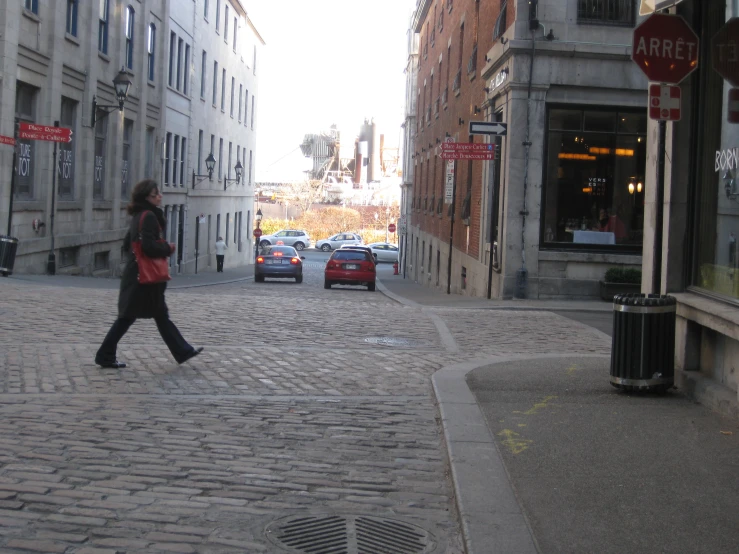 a woman walking on an old cobblestone street
