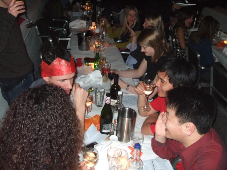 group of people sitting down at dinner with one holding a glass in his hand