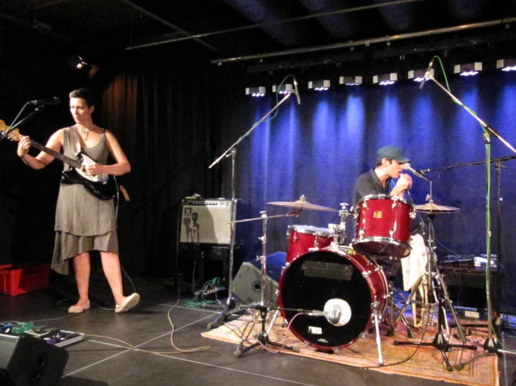 two people are singing and playing on stage