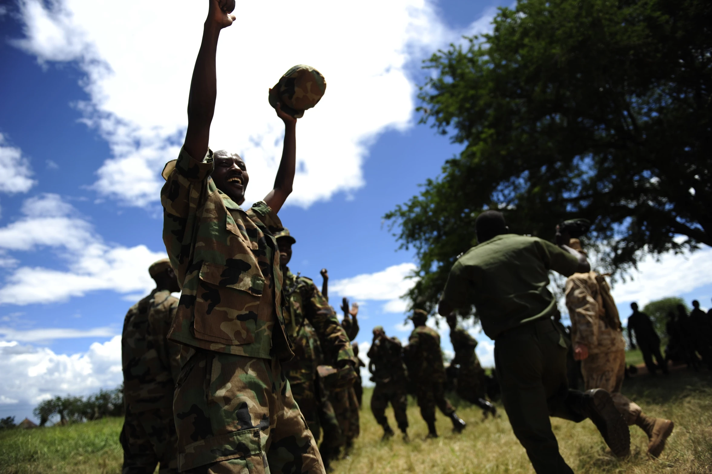 soldiers walking through a field and lifting a basketball in the air