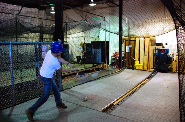 a man swings a baseball bat in a batting cage