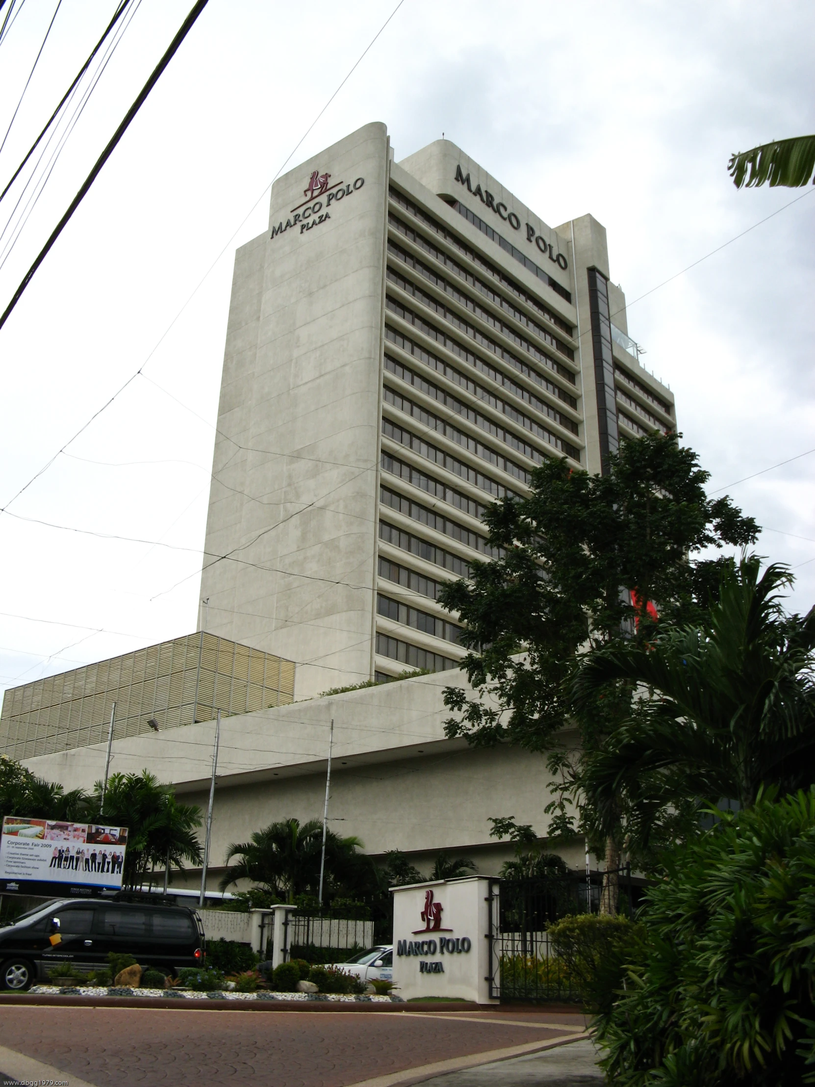 some vehicles are parked on the side of the road near a large building