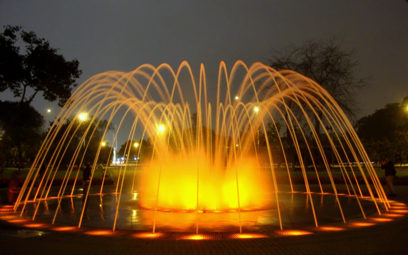 a fountain with orange lights at night time