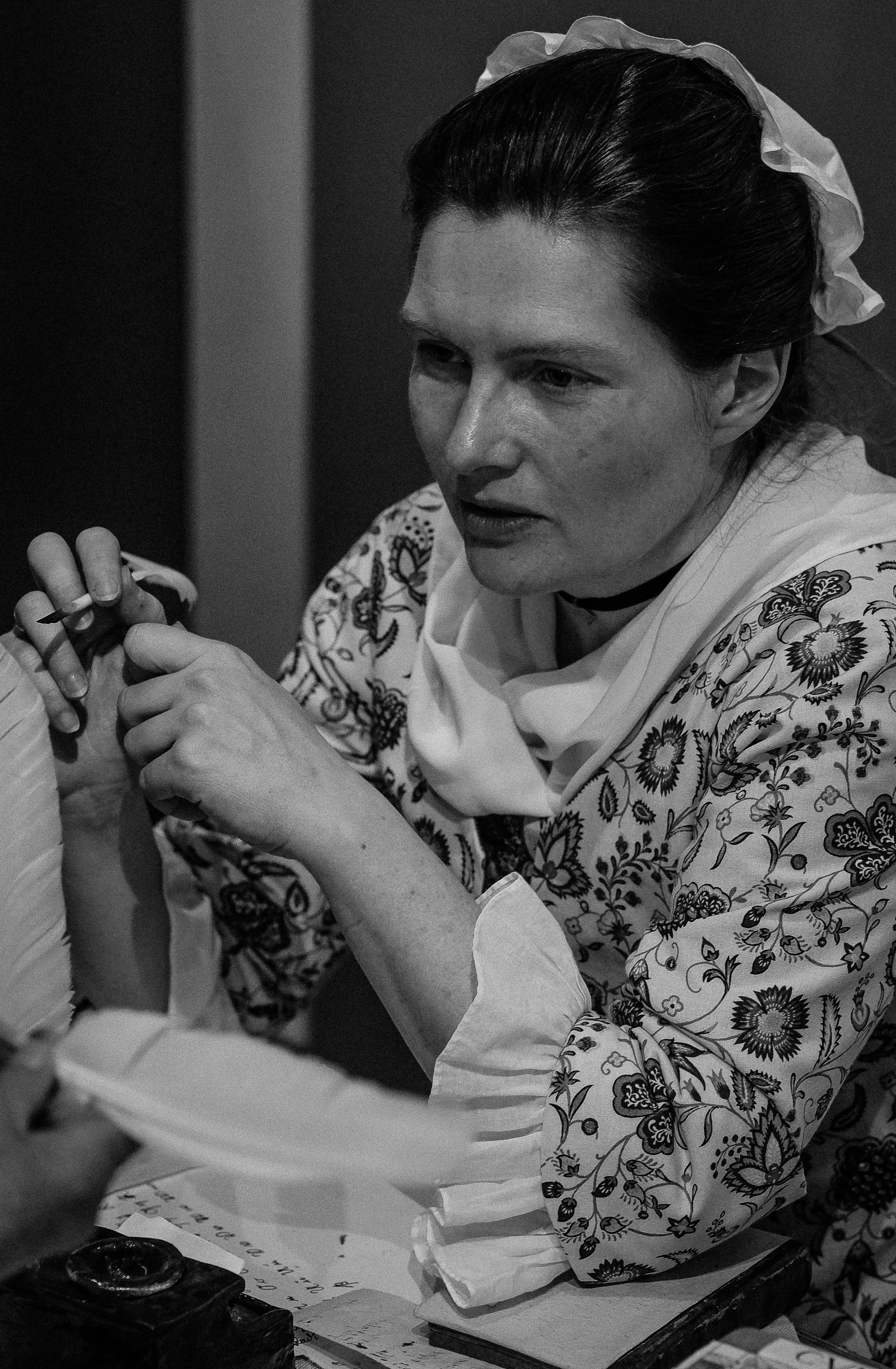black and white pograph of woman at table stitching