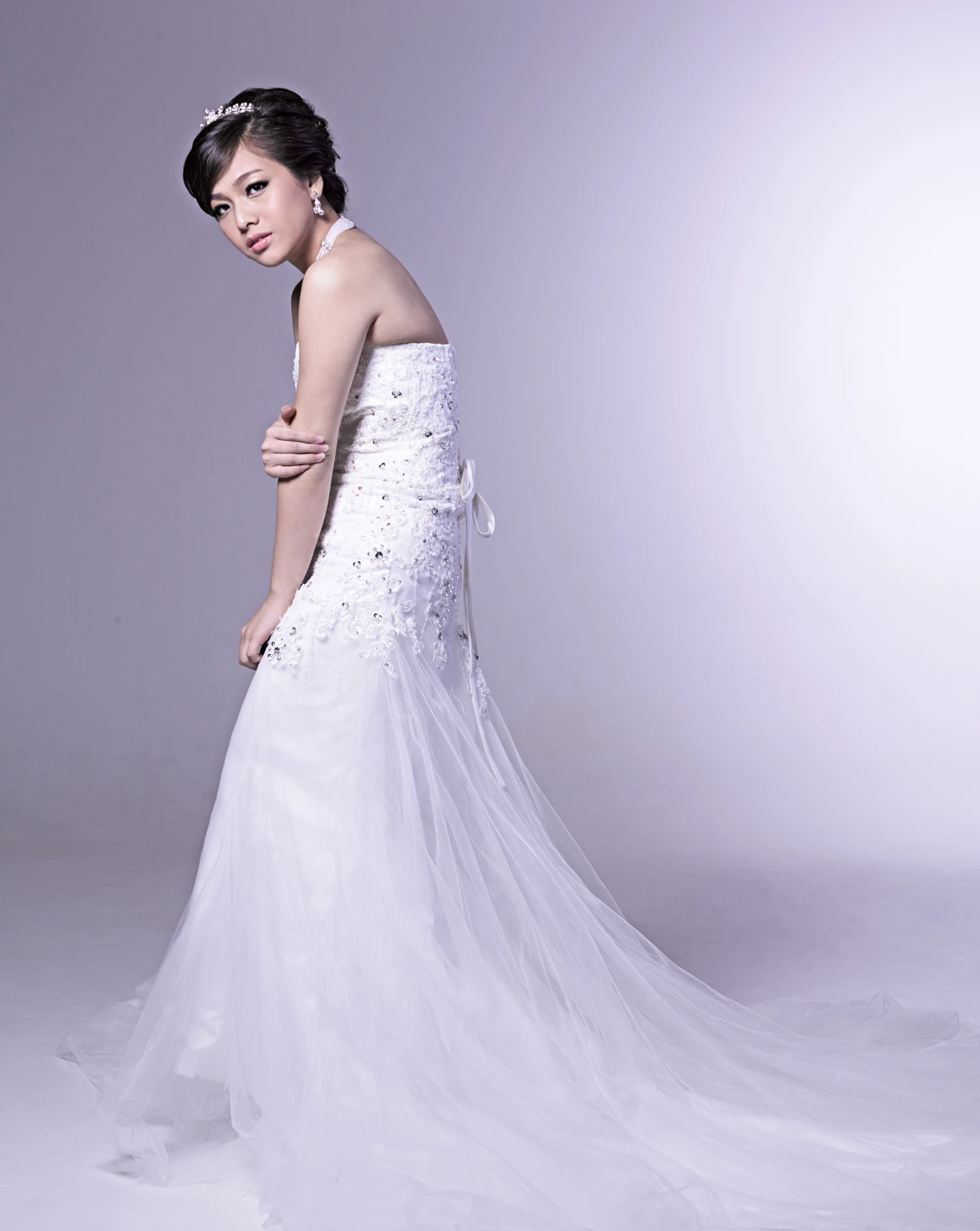 an asian bride poses with her wedding dress on