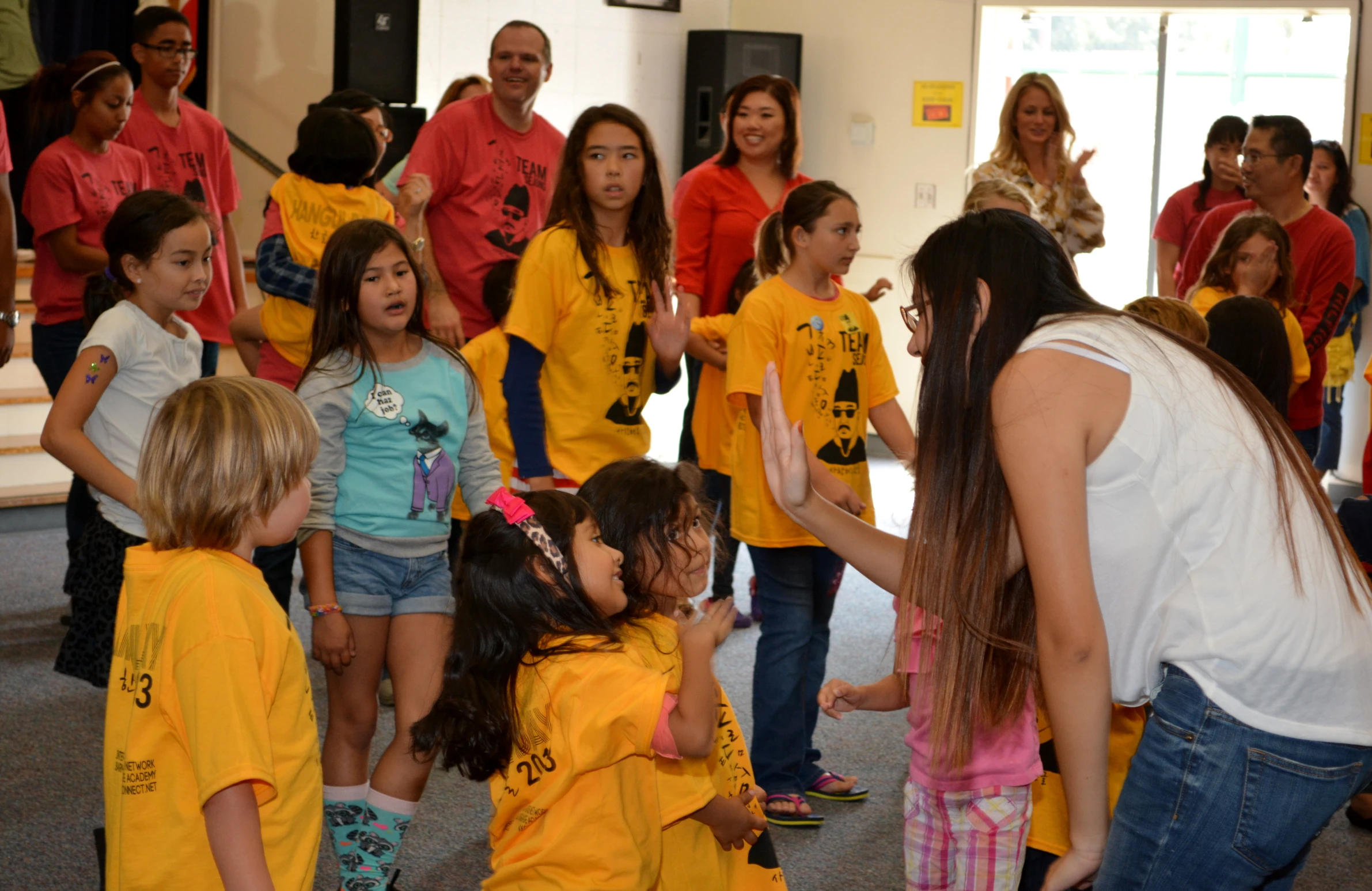 group of people wearing yellow shirts watching a girl in a white t - shirt