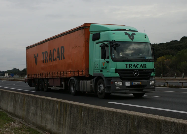 green and orange semi truck traveling on road