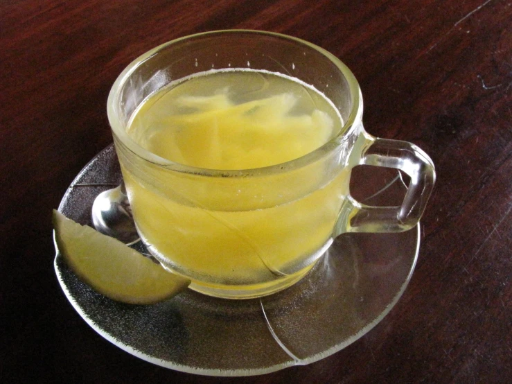 a glass mug of liquid and a slice of lemon on a saucer