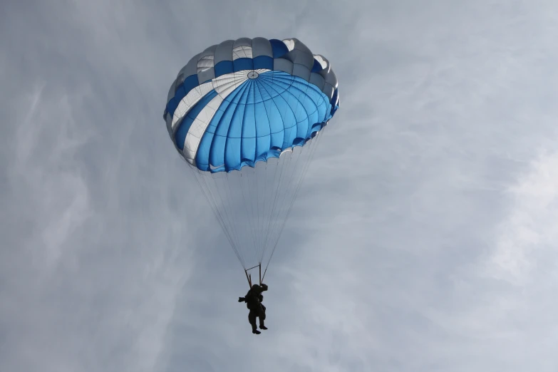 a person with a parachute flies through the air