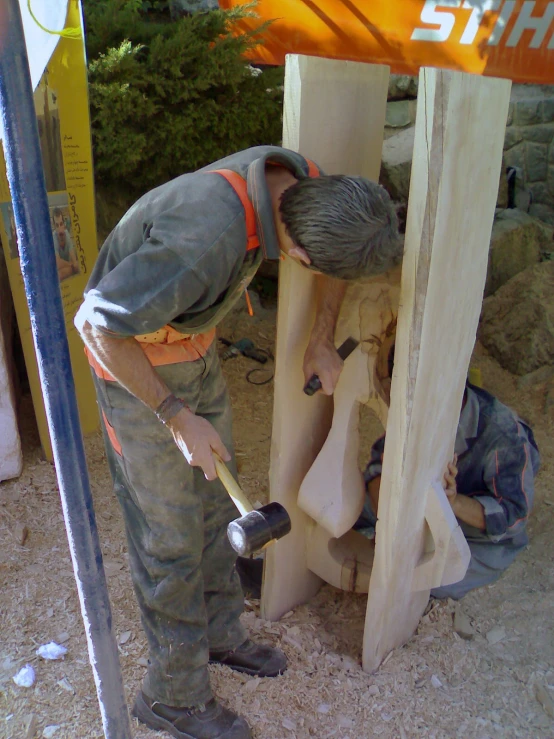 a person in work gear working on a wooden structure