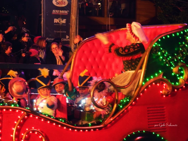 an elaborately decorated red carriage with a woman in the center and people behind