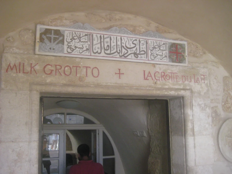 a man standing at an open door that reads milk grotto