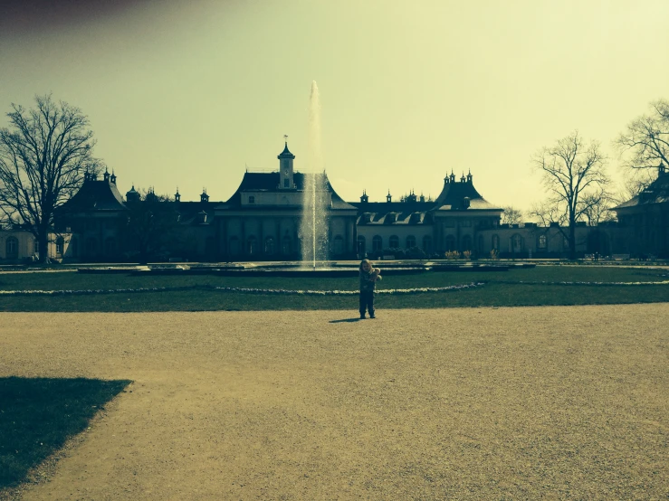 a man standing in front of a large building with water shooting up