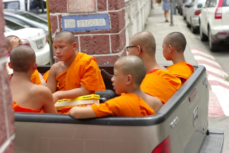 six monks sitting in the back of a truck