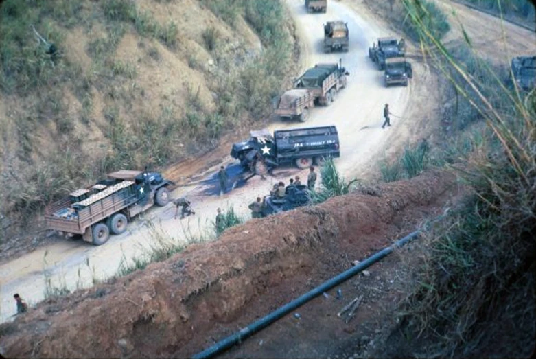 some trucks and a dump truck on a hill road