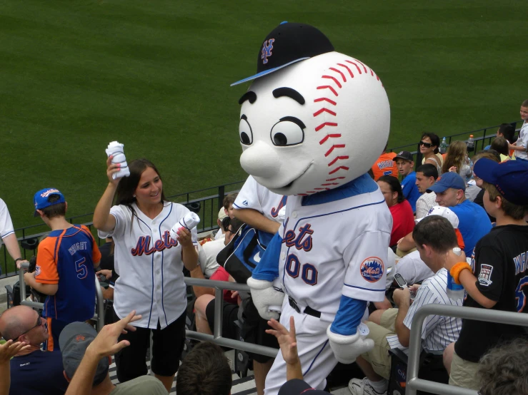 a person with a giant baseball mascot in a dugout