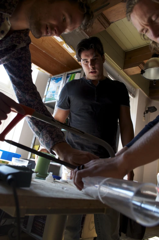 men standing around working on soing at a table