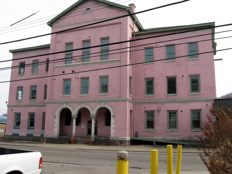 the building has pink paint and there are yellow poles in front of it