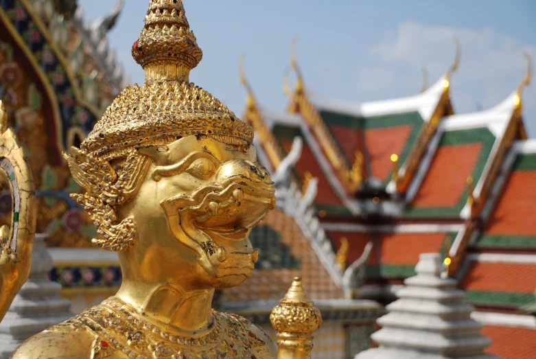 gold sculptures in front of a row of buddhist buildings