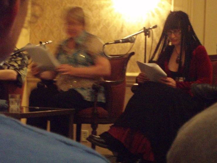 three women sitting in a room together, with one reading