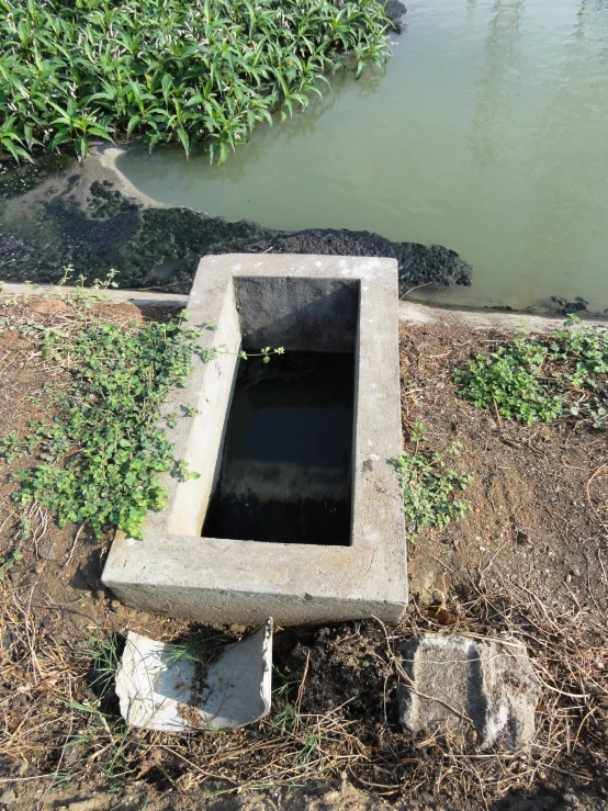 an old concrete trough near some water and a rock ledge