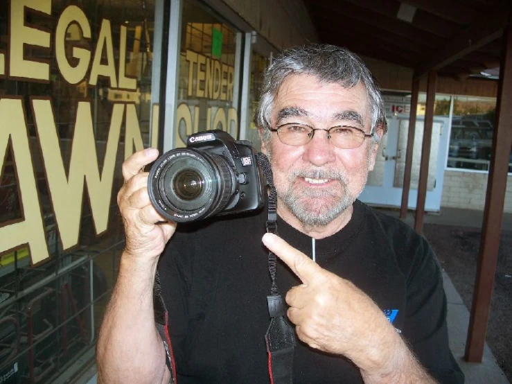 the man is holding a camera as he poses for a po