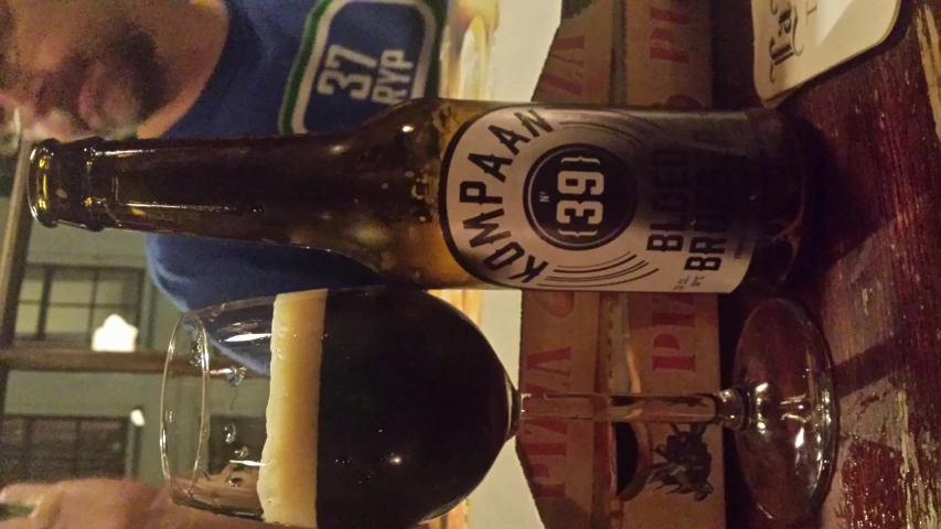 two men sitting at a bar looking at beers in glasses