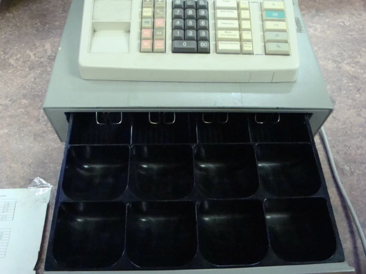 a cash register with cups below it in a drawer