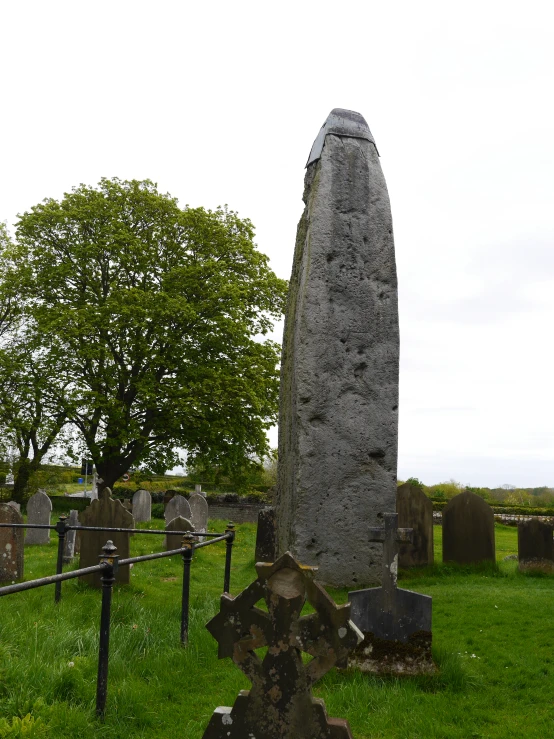 the old tombstone with green grass and an old stone tree