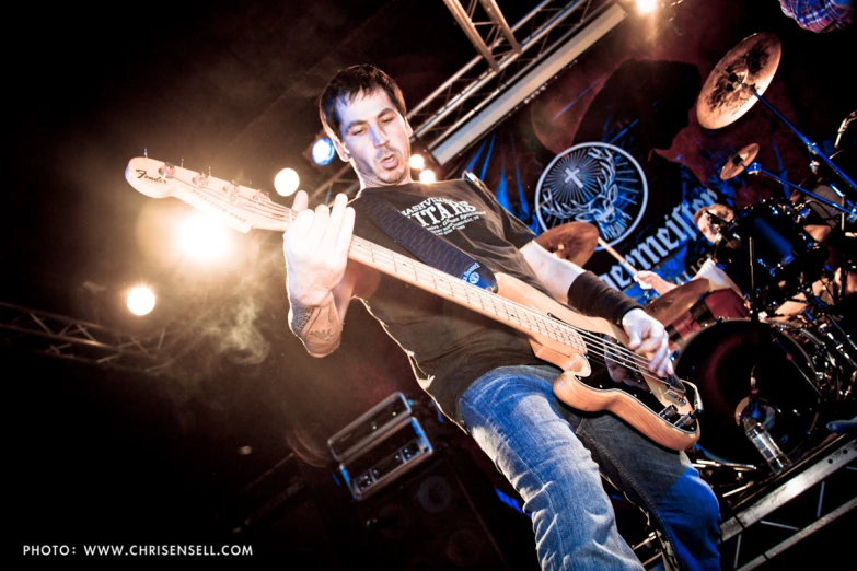 a male in a black shirt is playing a guitar