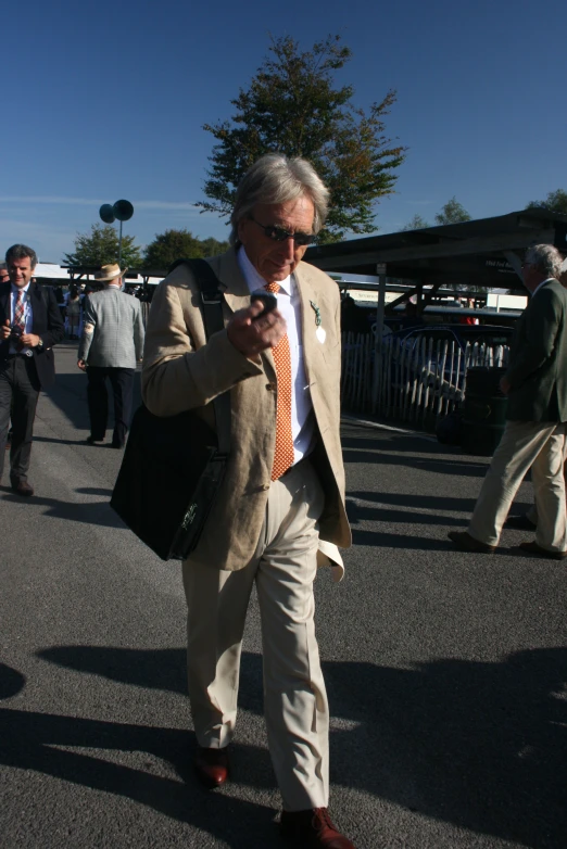 an older man in a tan suit walks on the street