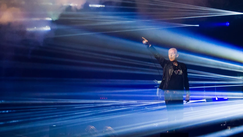 a man that is standing on a stage in front of some lights