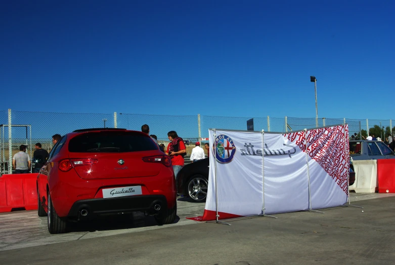 red car with tarp covered covering parked near fence