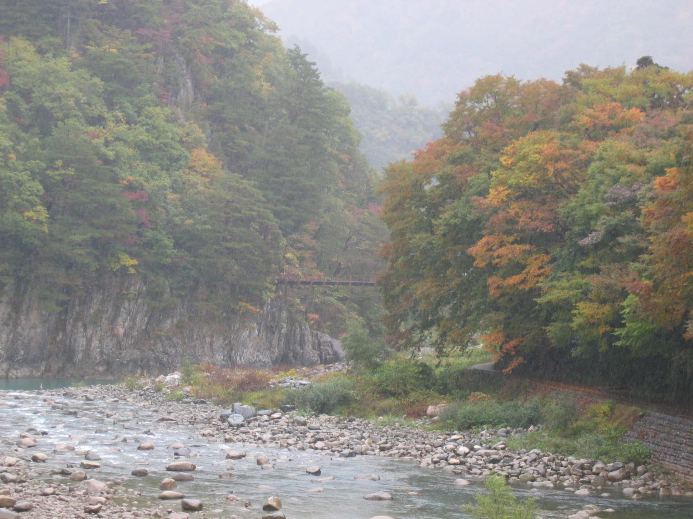 a scenic river scene with rocks and trees in the foreground